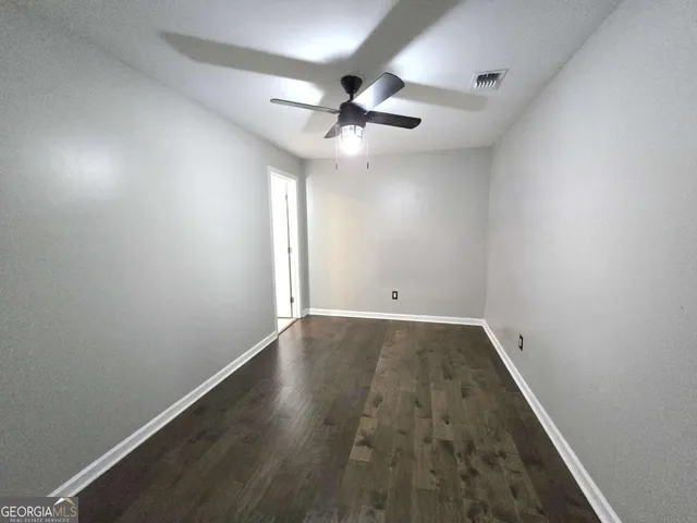 an empty room with wooden floor and ceiling fan