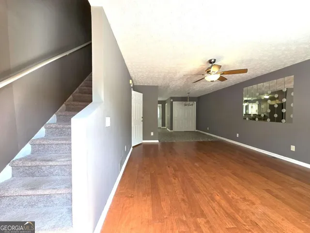 a view of a livingroom with wooden floor and stairs