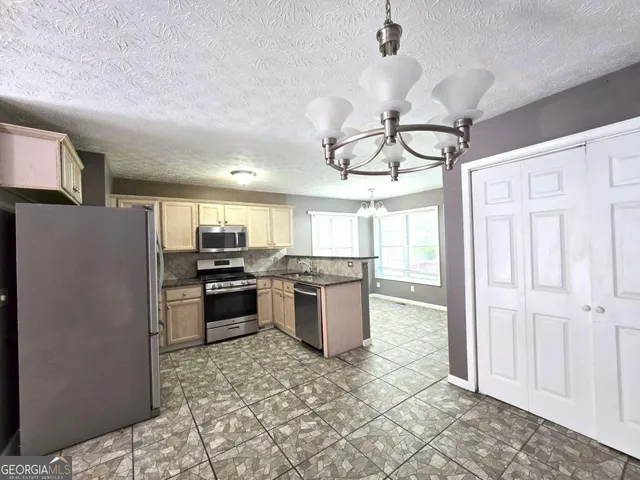 a kitchen with a chandelier stainless steel appliances cabinets and a counter top space