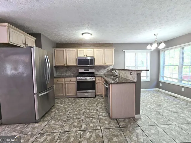 a kitchen with stainless steel appliances granite countertop a refrigerator stove top oven and sink