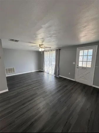 an empty room with wooden floor and windows
