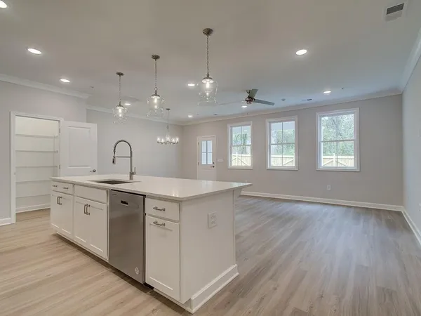 a large kitchen with stainless steel appliances granite countertop a sink dishwasher a stove and white countertops with wooden floor