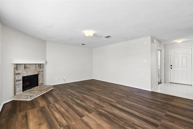 a view of empty room with wooden floor and fireplace