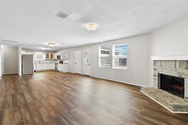 a view of empty room with a fireplace and wooden floor