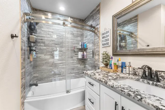 a bathroom with a granite countertop sink mirror bathtub and shower