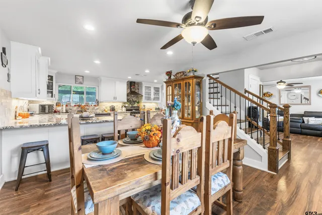 a open kitchen with stainless steel appliances granite countertop a dining table and chairs with wooden floor