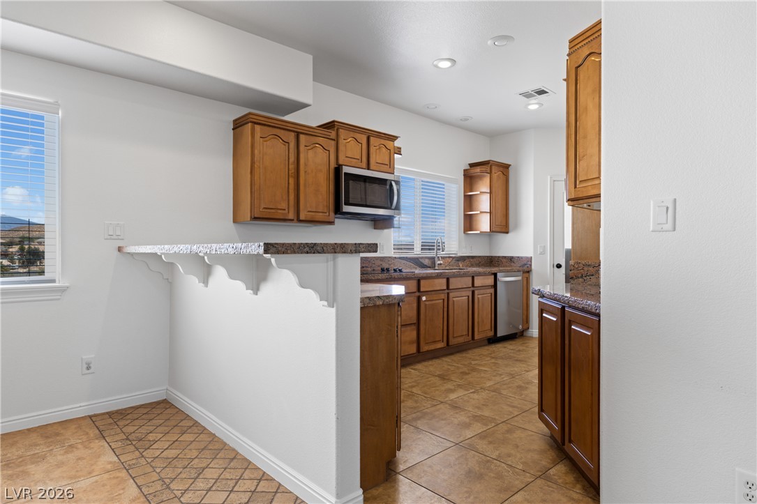 575 Gann Avenue Logandale, NV 89021 - Photo 16 of 75 A well-appointed kitchen features wood cabinetry, granite countertops, and tile flooring, ready for culinary endeavors.