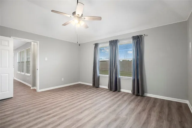 wooden floor in an empty room with a chandelier fan