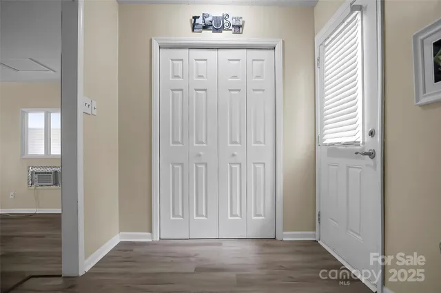 an empty room with wooden floor closet and windows