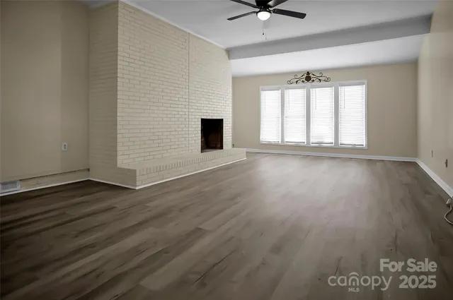 an empty room with wooden floor fan and windows
