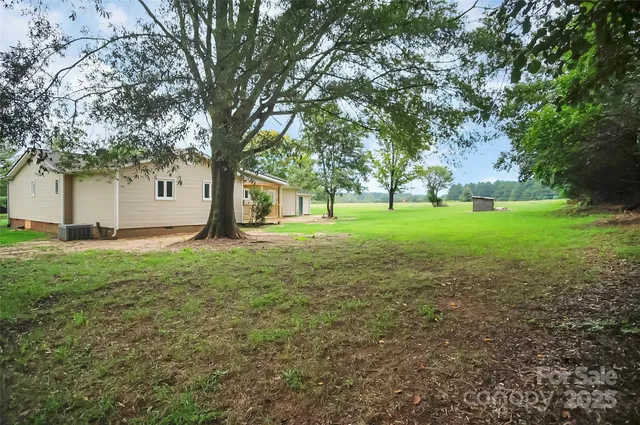 a view of a house with a big yard and large trees