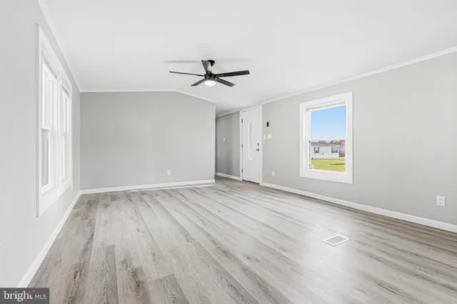 a view of empty room with wooden floor and fan