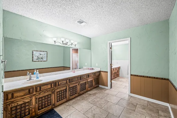 a spacious bathroom with a double vanity sink a mirror and a bathtub