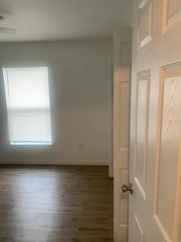an empty room with wooden floor and windows with curtains