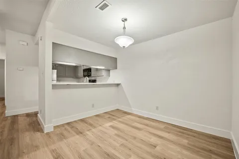 a view of an empty room with wooden floor fireplace and a window