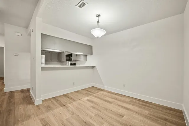 a view of an empty room with wooden floor fireplace and a window