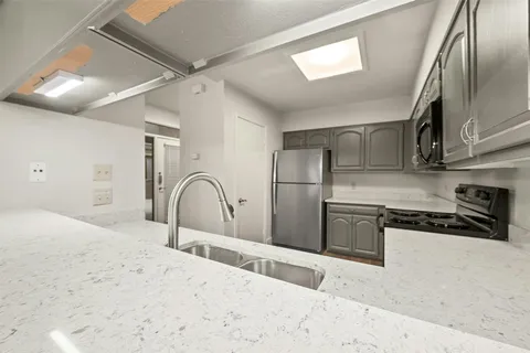 a kitchen with stainless steel appliances granite countertop a refrigerator a stove and a sink with wooden cabinets