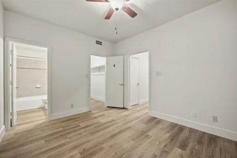 an empty room with wooden floor a ceiling fan and staircase