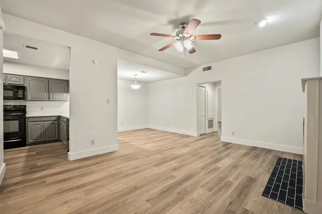 a view of an empty room with kitchen and a window