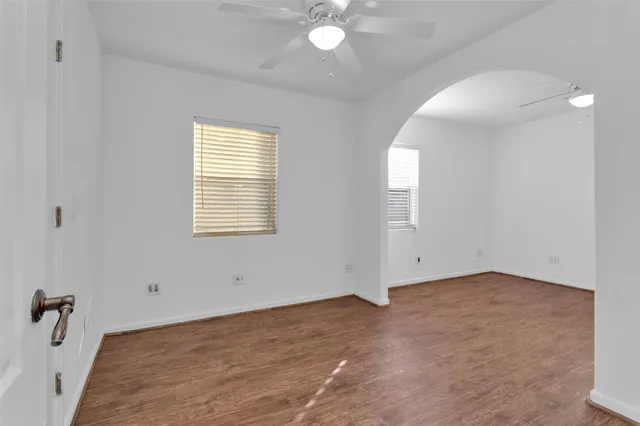a view of an empty room with window and wooden floor
