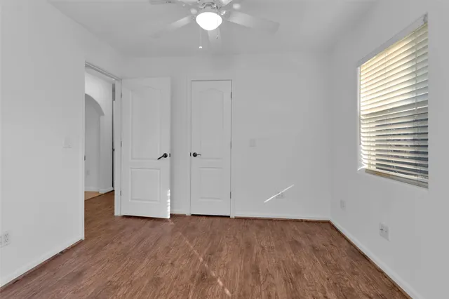 an empty room with wooden floor and windows