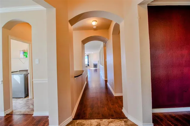 a view of a hallway with wooden floor and a bathroom