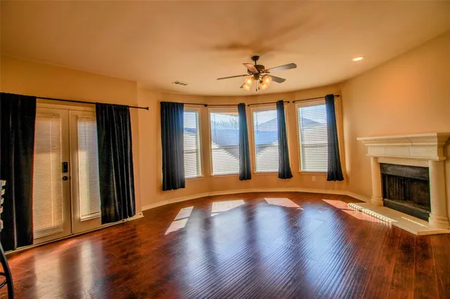 a view of an empty room with window and wooden floor