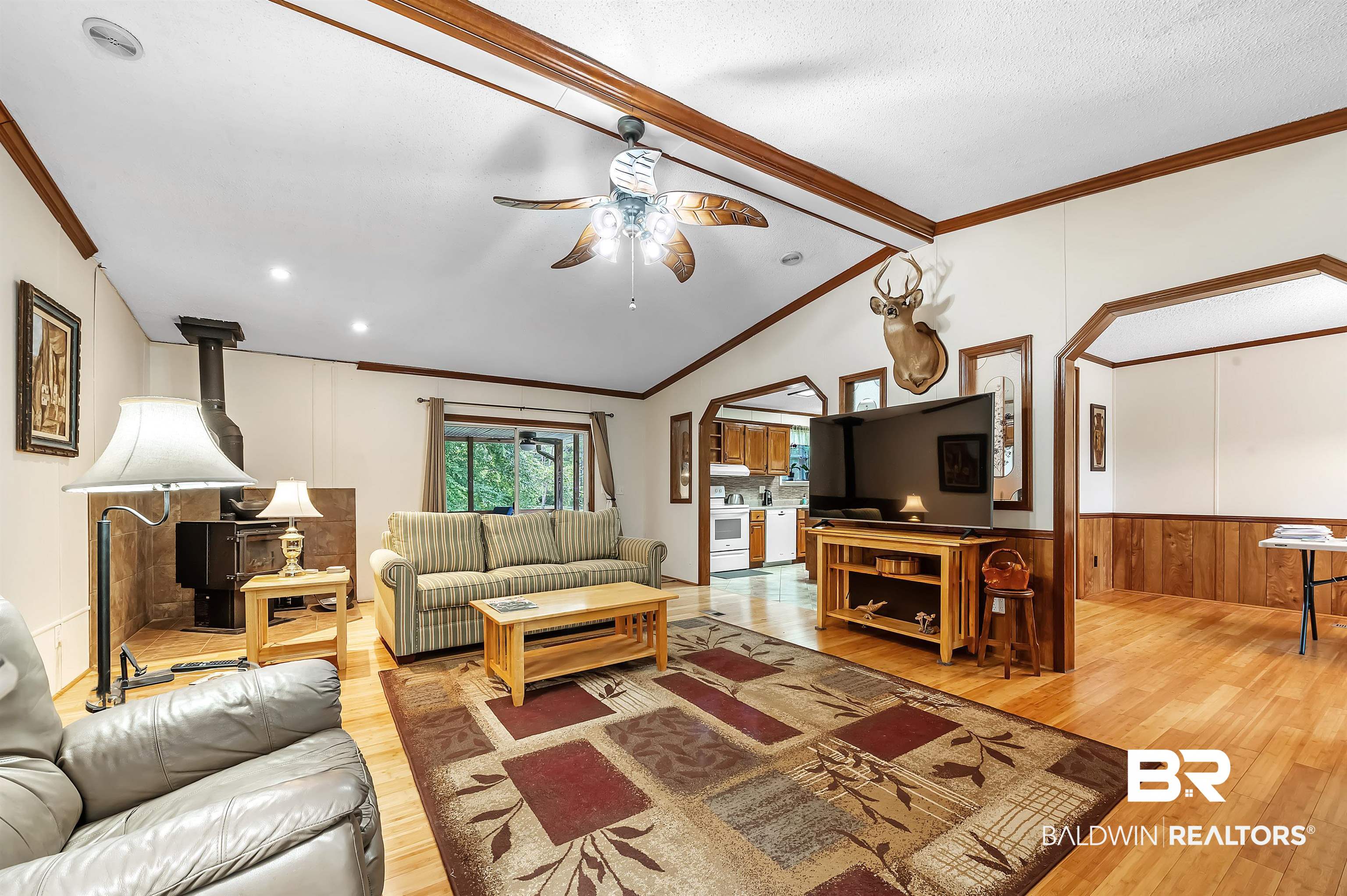10970 Stucki Road Elberta, AL 36530 - Photo 17 of 56 Living room featuring vaulted ceiling, a wood stove, ceiling fan, and Bamboo flooring