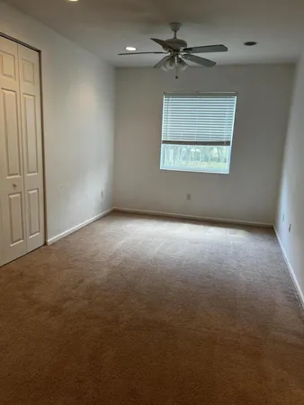 an empty room with windows and fan