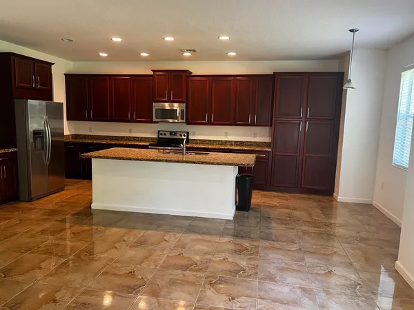 a large kitchen with stainless steel appliances granite countertop a stove a sink and a refrigerator