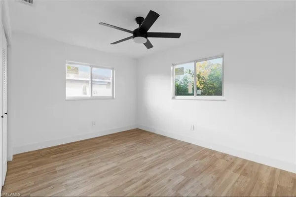 a view of empty room with wooden floor and fan