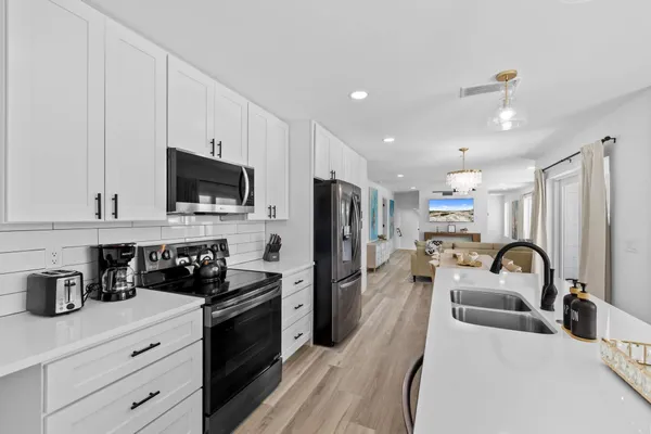 a kitchen with stainless steel appliances a stove a sink a refrigerator cabinets and a dining table