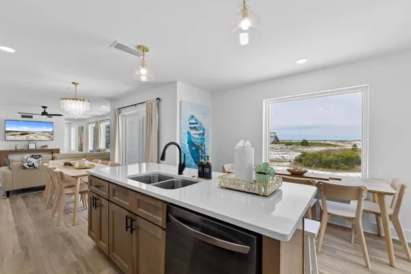 a kitchen with stainless steel appliances granite countertop a stove top oven a sink dishwasher and white cabinets with wooden floor