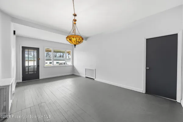 a view of an empty room with window and wooden floor