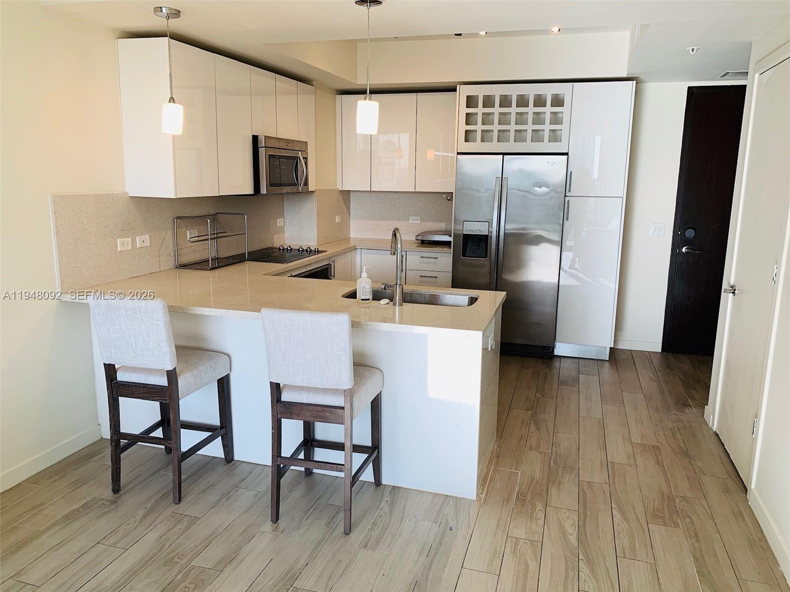 999 Southwest 1st Avenue, Unit 2310 Miami, FL 33130 - Photo 10 of 17 a kitchen with stainless steel appliances a microwave a sink a stove a refrigerator and cabinets