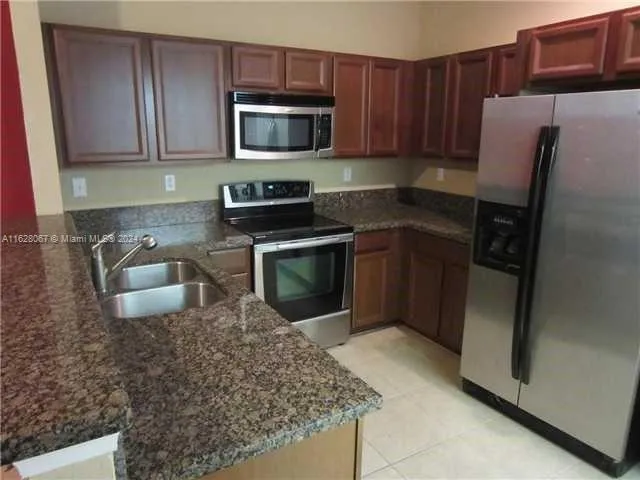 a kitchen with stainless steel appliances granite countertop a stove a microwave and a refrigerator