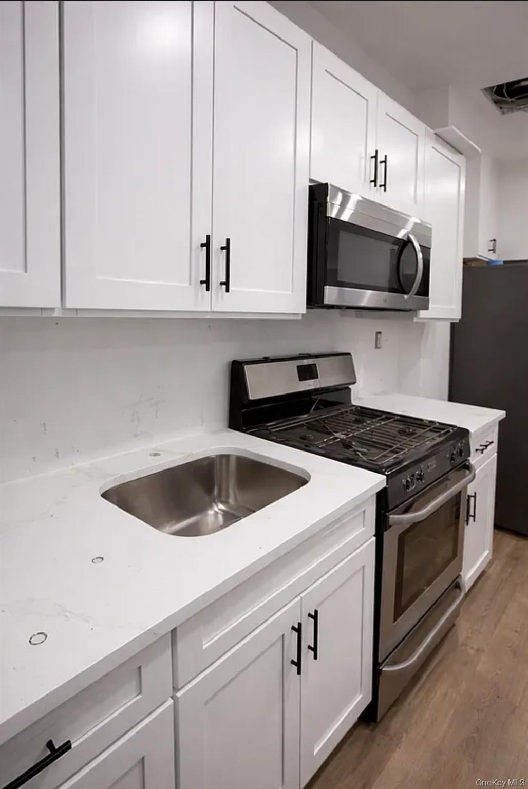 98-07 37th Avenue Queens, NY 11368 - Photo 3 of 5 a kitchen with stainless steel appliances granite countertop a sink a stove and microwave