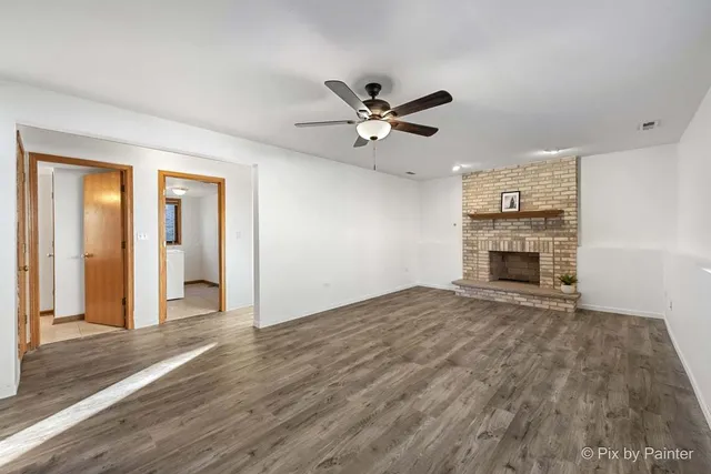 a view of empty room with wooden floor and fireplace