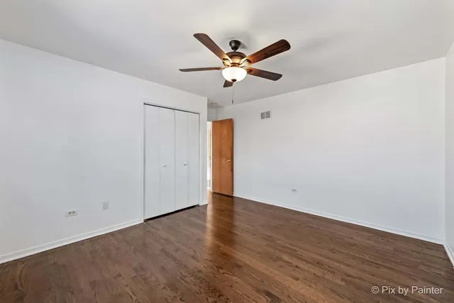 an empty room with wooden floor and ceiling fan