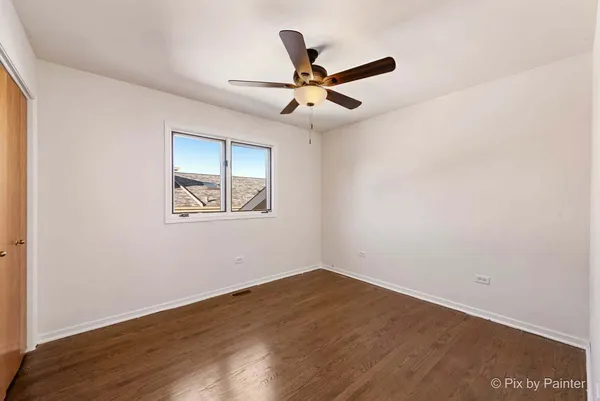 an empty room with wooden floor ceiling fan and window