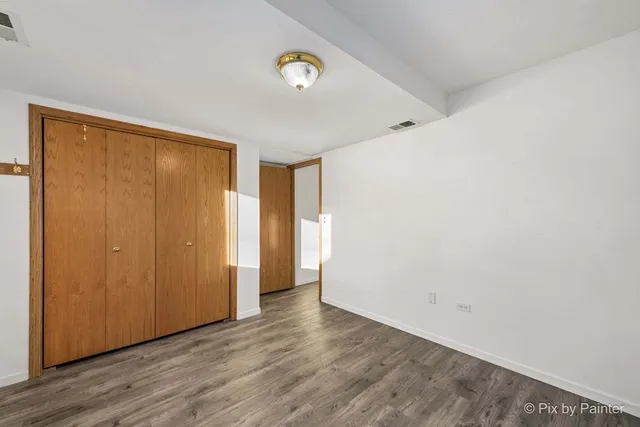 a view of an empty room with wooden floor and closet