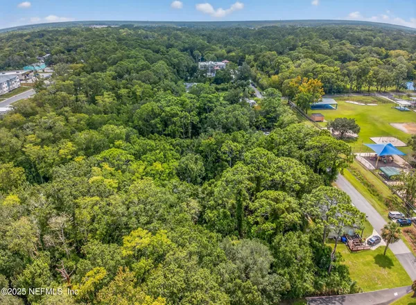 an aerial view of residential houses with outdoor space and trees