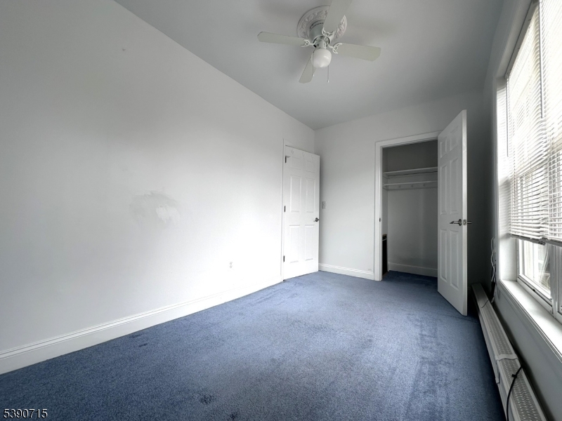 89 Getty Avenue, Unit 3 Clifton, NJ 07011 - Photo 17 of 28 an empty room with windows and fan chandelier
