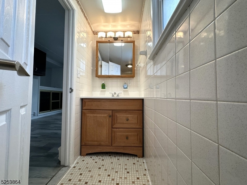 89 Getty Avenue, Unit 3 Clifton, NJ 07011 - Photo 4 of 28 a bathroom with a sink a mirror and shower