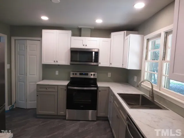 a kitchen with stainless steel appliances granite countertop a stove a sink and a microwave