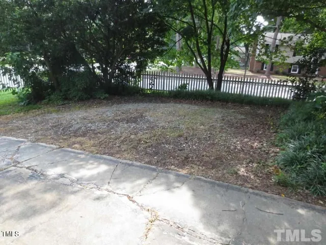 a view of a yard with large trees and wooden fence