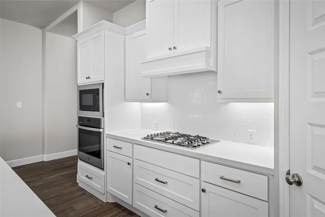 a kitchen with white cabinets and appliances