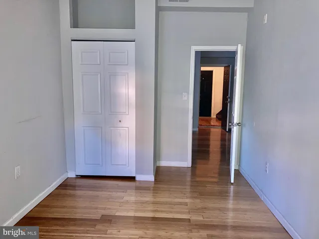 a view of a hallway with wooden floor and closet
