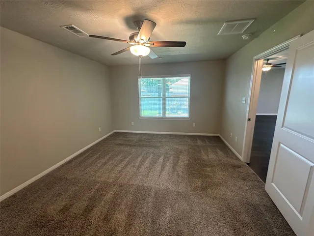 an empty room with a chandelier fan and windows