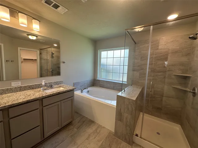a bathroom with a tub sink shower and mirror